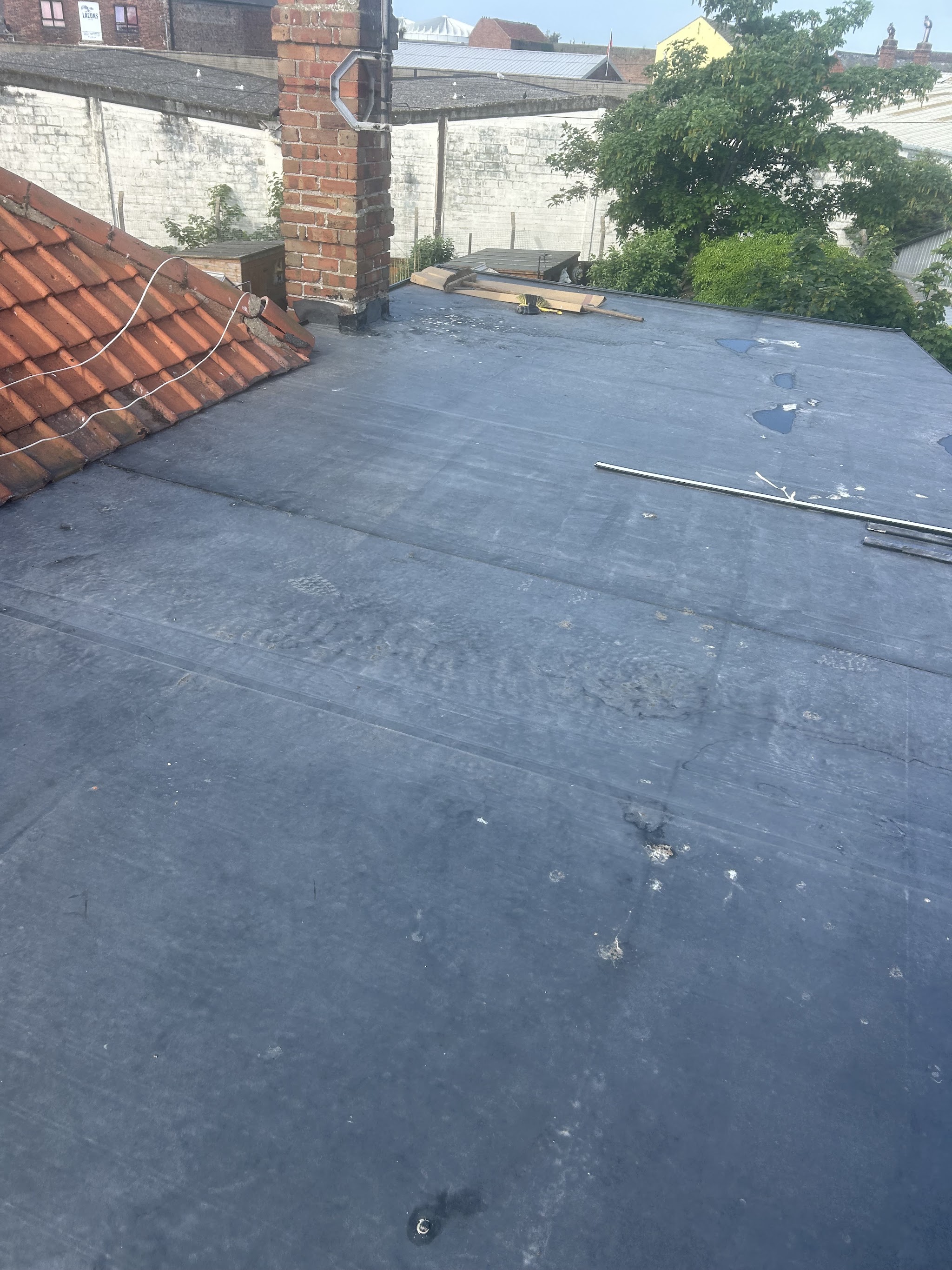 A finished flat roof beside a tiled roof and chimney