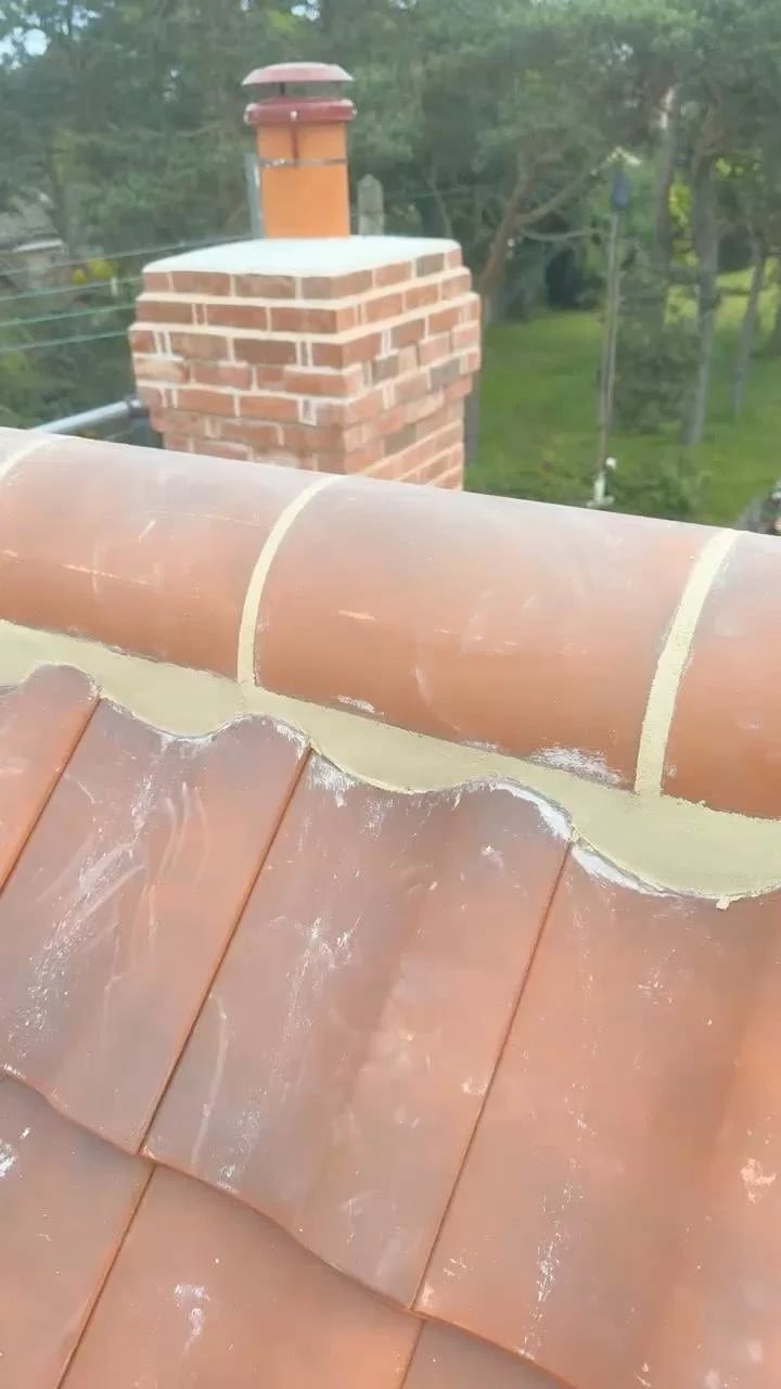 A rebuilt brick chimney with a terracotta pot and new ridge tiles